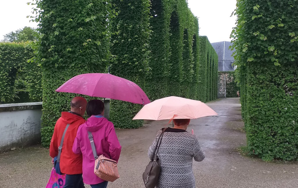 3 SHG-Mitglieder mit Schirmen unterwegs im Schlossgarten